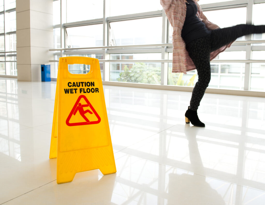 woman slipping next to a wet floor sign